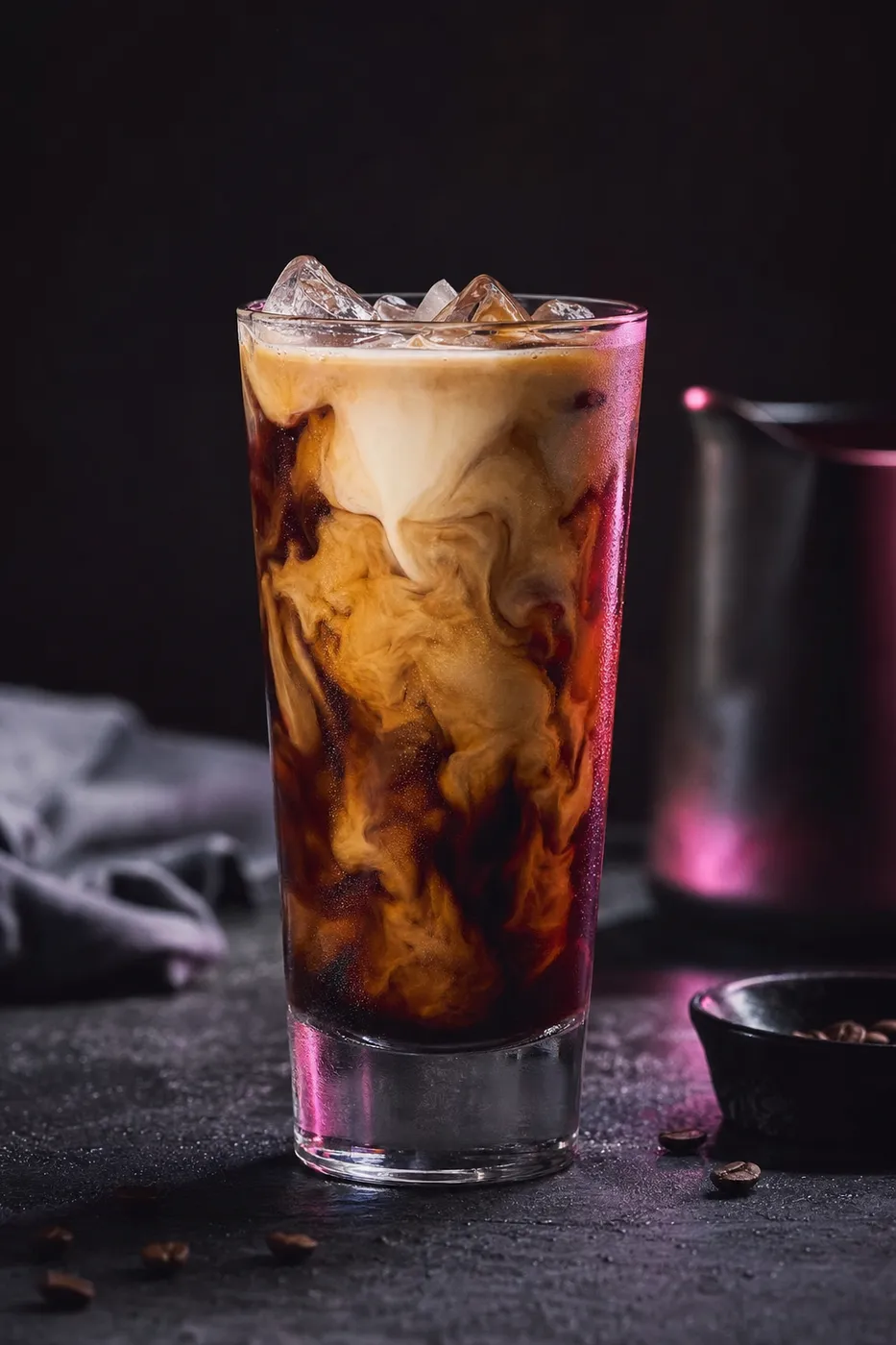 Hohes Glas Eiskaffee mit marmorierter Milch und großen Eiswürfeln auf dunklem Stein